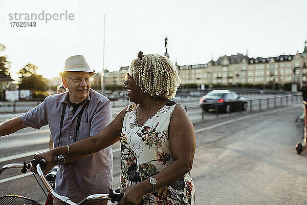 Fröhliches Paar mit Fahrrad auf der Straße in der Stadt