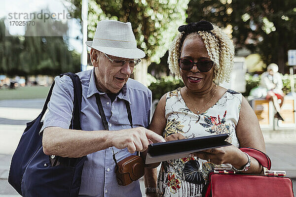 Lächelnde Senior Paar mit digitalen Tablette auf der Straße während sonnigen Tag