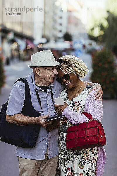 Senior Mann umarmt Frau  während auf der Straße in der Stadt stehen
