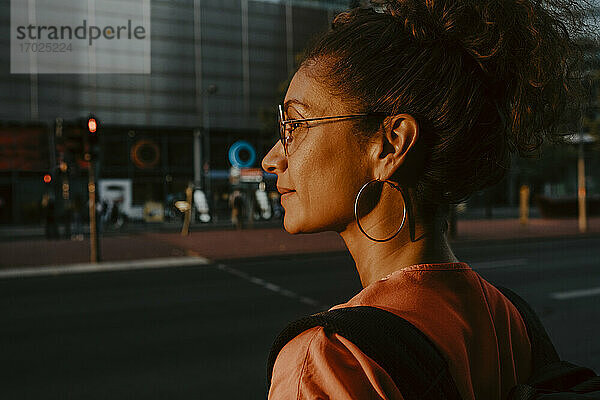 Geschäftsfrau schaut weg in der Stadt während des Sonnenuntergangs