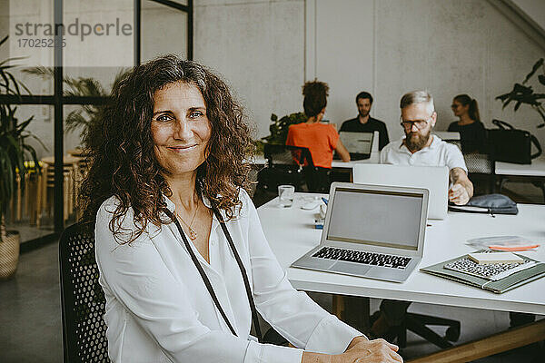 Porträt von lächelnden Geschäftsfrau sitzt von Laptop in Coworking Büro