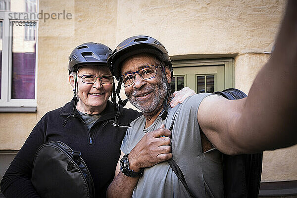 Aktives Seniorenpaar macht Selfie mit Fahrradhelm auf dem Balkon