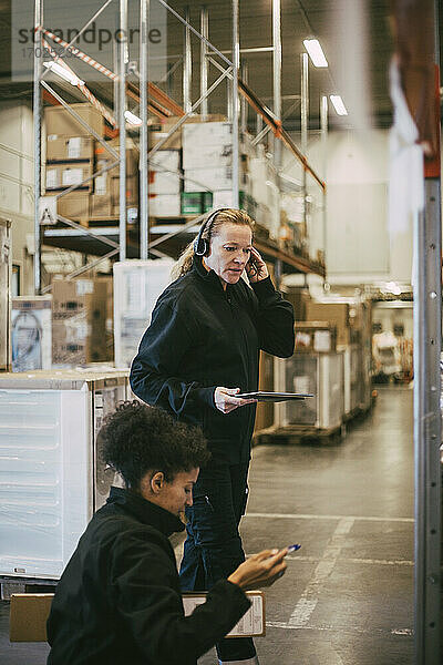Weibliche Arbeiter beim Analysieren  während sie ein digitales Tablet im Logistiklager halten