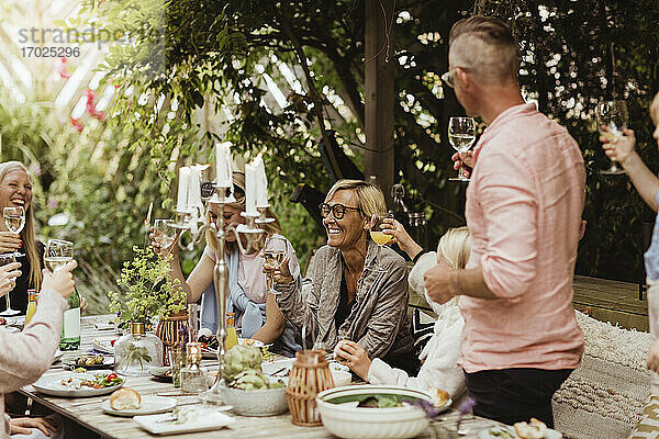 Fröhliche Familie mit Trinkspruch mit Weinglas beim Abendessen Partei im Vorgarten