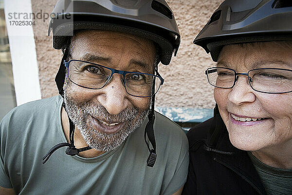 Lächelndes Paar mit Fahrradhelm vor dem Haus