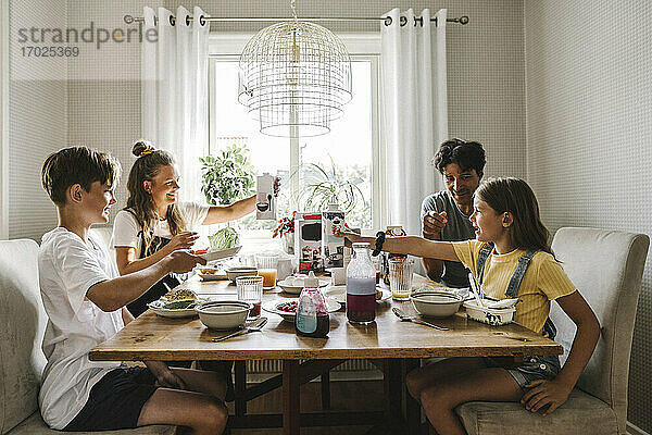 Eltern frühstücken mit Kindern am Tisch zu Hause