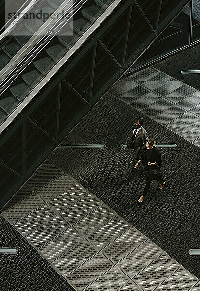 Hohe Winkel Ansicht von männlichen und weiblichen Unternehmern zu Fuß durch Rolltreppe auf Gehweg