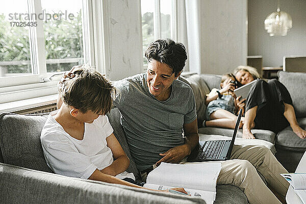 Glücklicher Vater mit Sohn macht seine Hausaufgaben zu Hause