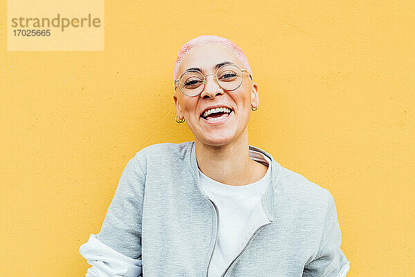 Porträt einer glücklichen jungen Frau mit kurzen rosa Haaren  die eine Brille trägt