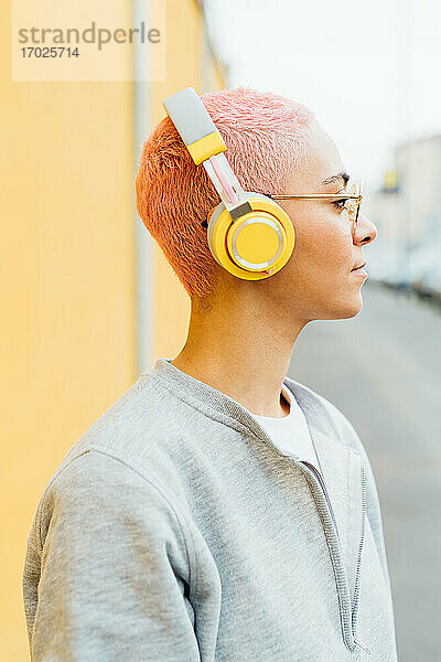 Porträt einer Frau mit kurzen rosa Haaren  die Kopfhörer trägt