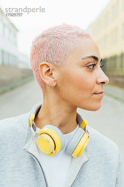 Porträt einer jungen Frau mit kurzen rosa Haaren  die Kopfhörer trägt