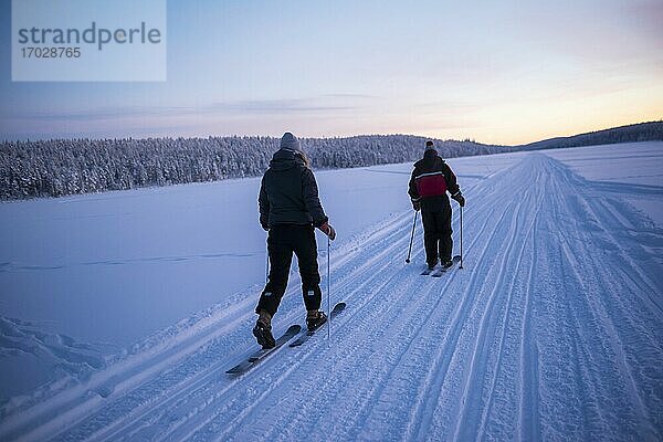 Skifahren auf dem zugefrorenen See von Torassieppi bei Sonnenuntergang  Lappland  Finnland
