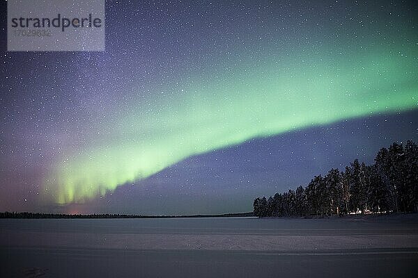 Nordlicht (Aurora borealis) über einem schneebedeckten  vereisten See im Winter in Finnisch-Lappland  innerhalb des Polarkreises in Finnland