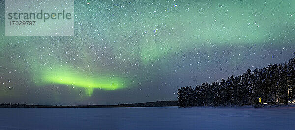 Nordlicht (Aurora Borealis) über einem schneebedeckten  zugefrorenen See im Winter in Finnisch-Lappland  innerhalb des Polarkreises in Finnland