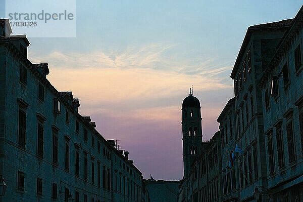 Foto der Silhouette des Franziskanerklosters bei Sonnenuntergang  Stradun  Altstadt von Dubrovnik  Kroatien. Dies ist ein Foto von einer Silhouette des Franziskanerklosters in der Altstadt von Dubrovnik bei Sonnenuntergang. Das Franziskanerkloster ist ein christliches Kloster aus dem 14. Jahrhundert  das sich am Stradun  der berühmten Hauptstraße in der Altstadt von Dubrovnik  befindet. Es sind berühmte  alte  historische Gebäude wie das Franziskanerkloster  die großartige Beispiele für romanische und venezianisch-gotische Architektur sind  die dazu geführt haben  dass die Altstadt von Dubrovnik in die Liste des UNESCO-Weltkulturerbes aufgenommen wurde.