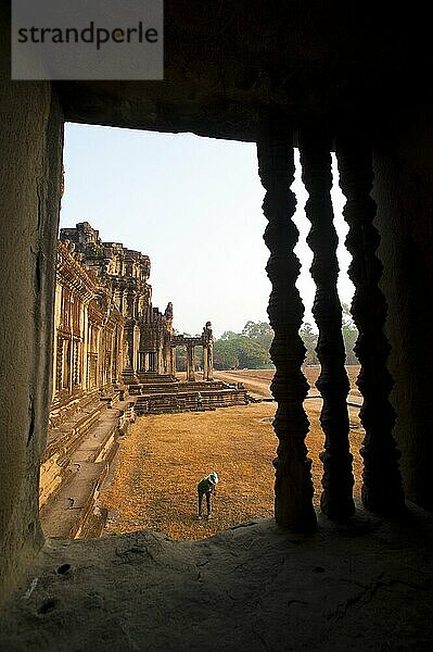Frau bei der Gartenarbeit in Angkor Wat  Kambodscha. Angkor Wat wurde im 12. Jahrhundert von Suryavarman II. erbaut. Obwohl Angkor Wat ursprünglich dem Hindu-Gott Vishnu gewidmet war  ist es heute ein buddhistischer Tempel. Angkor Wat ist der berühmteste Tempel und steht daher bei den meisten Touristen ganz oben auf der Liste der Muss-Sehenswürdigkeiten und ist bei Sonnenaufgang und Sonnenuntergang extrem überlaufen. Es versteht sich von selbst  dass keine Reise zu den Angkor-Tempeln ohne einen Sonnenaufgang in Angkor Wat vollständig ist.