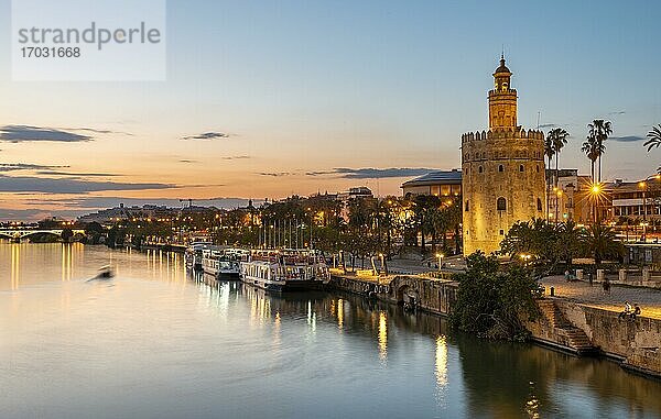 Blick über den Fluss Rio Guadalquivir mit Torre del Oro und Uferpromenade mit Ausflugsbooten  Sonnenuntergang  blaue Stunde  Sevilla  Andalusien  Spanien  Europa