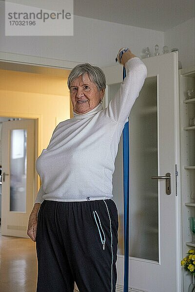 Seniorin  Frau 87 Jahre beim Turnen in der Wohnung  Fitness im Alter  Fitnessband  Oberbayern  Bayern  Deutschland  Europa