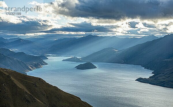 Sonnenstrahlen scheinen durch Wolkenhimmel  Blick auf Lake Wanaka im Abendlicht  See und Berglandschaft  Ausblick vom Isthmus Peak  Wanaka  Otago  Südinsel  Neuseeland  Ozeanien