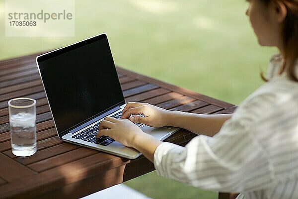 Japanerin arbeitet mit Laptop im Garten