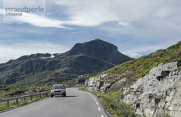 Auto auf Straße durch Tundra  Hinten Berg Bitihorn  Jotunheimen Nationalpark  Norwegen  Europa