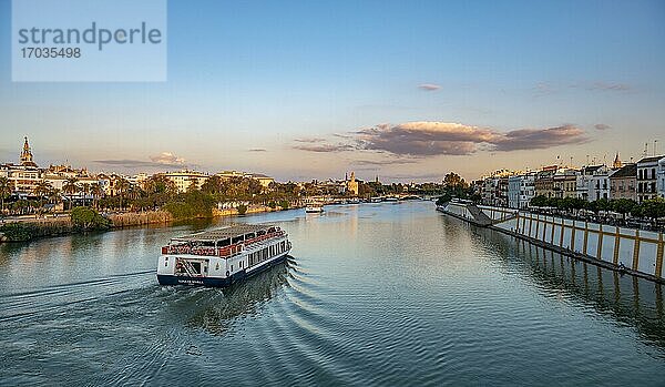 Blick über den Fluss Rio Guadalquivir mit Ausflugsbooten  Uferpromenade an der Calle Betis in Triana und Blick auf Torre del Oro  Sonnenuntergang  Sevilla  Andalusien  Spanien  Europa