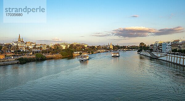 Blick über den Fluss Rio Guadalquivir mit Ausflugsbooten  Uferpromenade an der Calle Betis in Triana und Blick auf Torre del Oro  Sonnenuntergang  Sevilla  Andalusien  Spanien  Europa