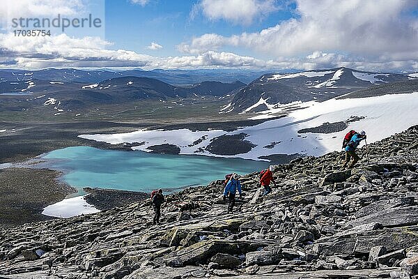 Tundra  karge Berglandschaft mit Gebirgssee  Wanderer auf Wanderung zum Berg Snøhetta  Dovrefjell Nationalpark  Oppdal  Norwegen  Europa