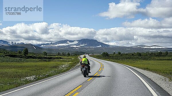 Motorradfahrer auf Straße durch Tundra  Landstraße  Dovrefjell Nationalpark  Oppdal  Norwegen  Europa
