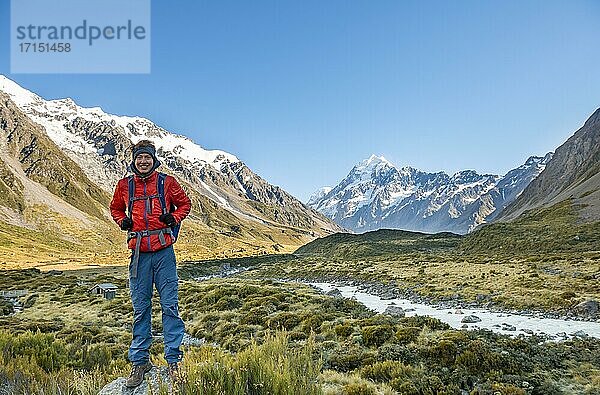 Wanderer steht auf einem Stein  Hooker Valley mit Blick auf schneebedeckten Mount Cook  Hooker River  schneebedeckten Mount Cook Nationalpark  Südalpen  Canterbury  Südinsel  Neuseeland  Ozeanien