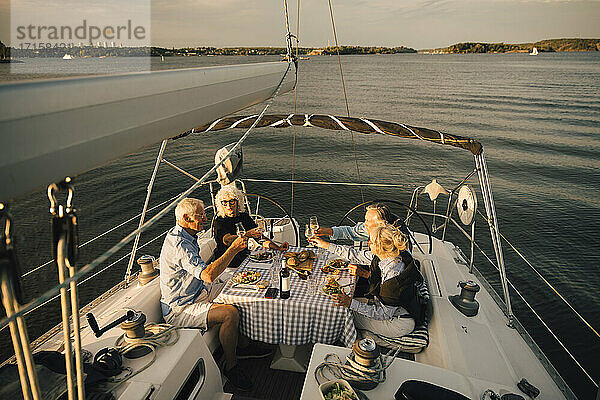 Heterosexuelle Paare stoßen mit Weingläsern an  während sie ihre Freizeit auf einem Segelboot verbringen