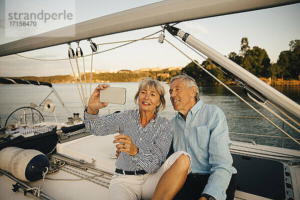 Lächelnde ältere Paar unter Selfie auf Smartphone  während in Boot sitzen