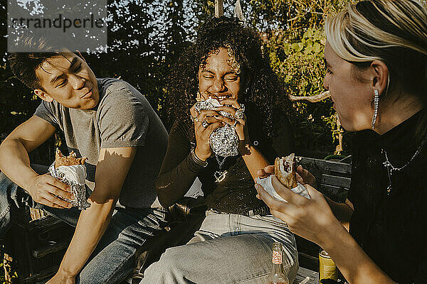Junge Frau isst Essen mit Freunden im Park