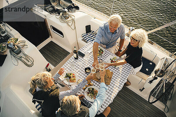 Hohe Winkel Ansicht der männlichen und weiblichen Freunde Toasting Weingläser am Tisch in Boot
