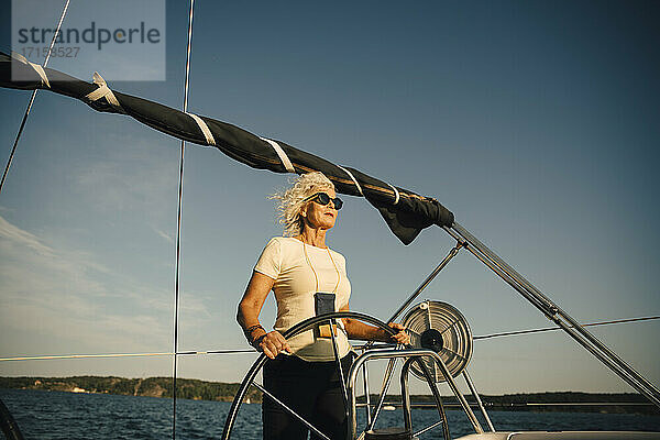 Aktive ältere Frau Segelboot gegen den Himmel im Meer an einem sonnigen Tag