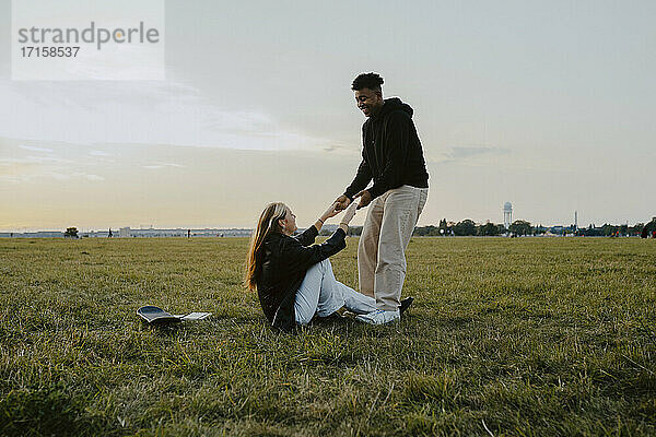 Lächelnder Mann  der die Hände seiner Freundin hält  die im Park sitzt