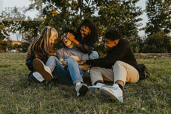 Junge männliche und weibliche Freunde spielen im Park bei Sonnenuntergang