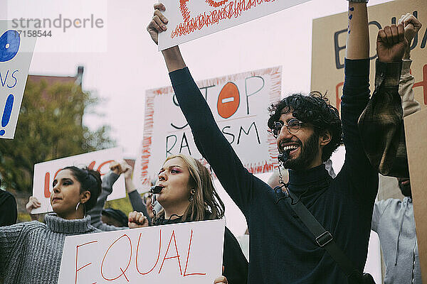 Lächelnder Mann mit weiblichen Aktivisten  die in einer sozialen Bewegung protestieren