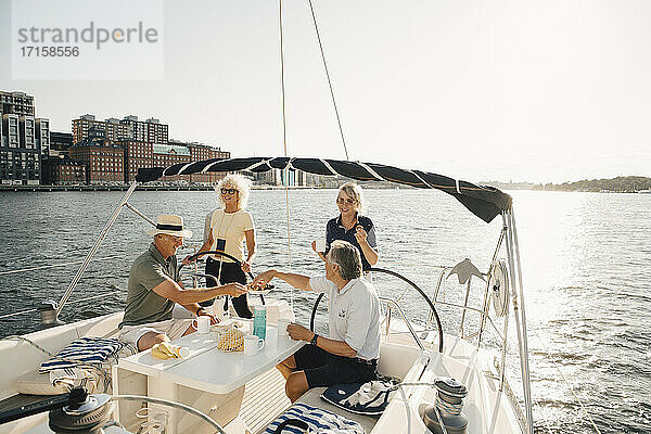 Senior Paare mit Essen  während in Boot gegen klaren Himmel sitzen