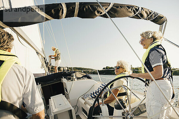 Senior männliche und weibliche Freunde verbringen Freizeit in Segelboot auf sonnigen Tag