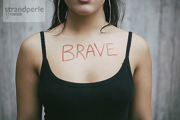 Midsection von weiblichen Aktivisten mit mutigen Text auf der Brust gegen die Wand geschrieben