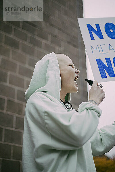 Weiblicher Demonstrant schreiend mit Schild während sozialer Bewegung