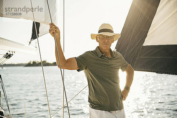 Porträt eines älteren Mannes  der ein Seil hält  während er an einem sonnigen Tag gegen das Meer steht