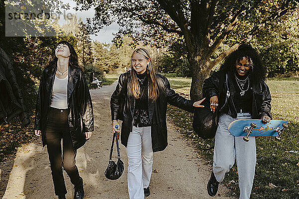 Fröhliche weibliche Freunde gehen zusammen im Park