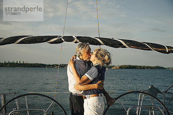 Senior Paar Lippe küssen in Boot gegen Meer und Himmel am sonnigen Tag