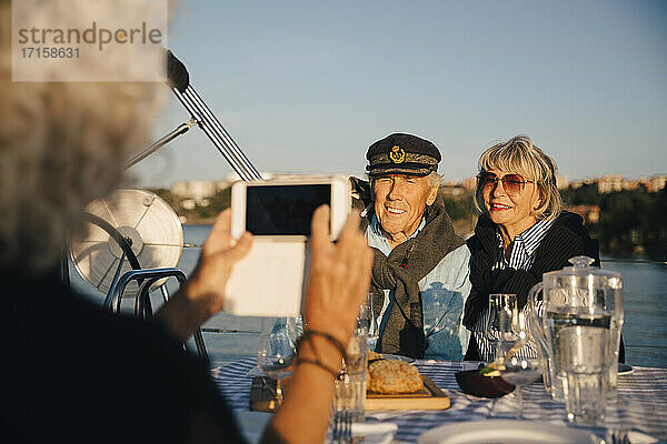 Ausgeschnittenes Bild von Frau fotografieren ältere Paar sitzt in Boot auf sonnigen Tag