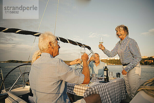 Fröhlich Senior Paare Toasting Weingläser in Boot gegen den Himmel auf sonnigen Tag