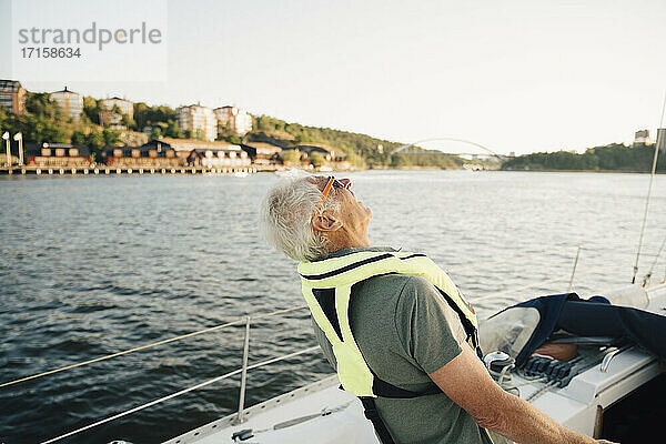 Senior Mann lachend im Boot gegen den Himmel am sonnigen Tag