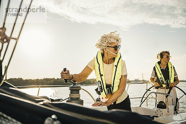 Weibliche Freunde schauen weg beim Segeln im Boot gegen den Himmel