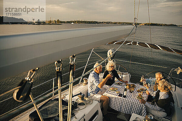 Ältere Paare stoßen mit Weingläsern an  während sie ihre Freizeit im Boot verbringen